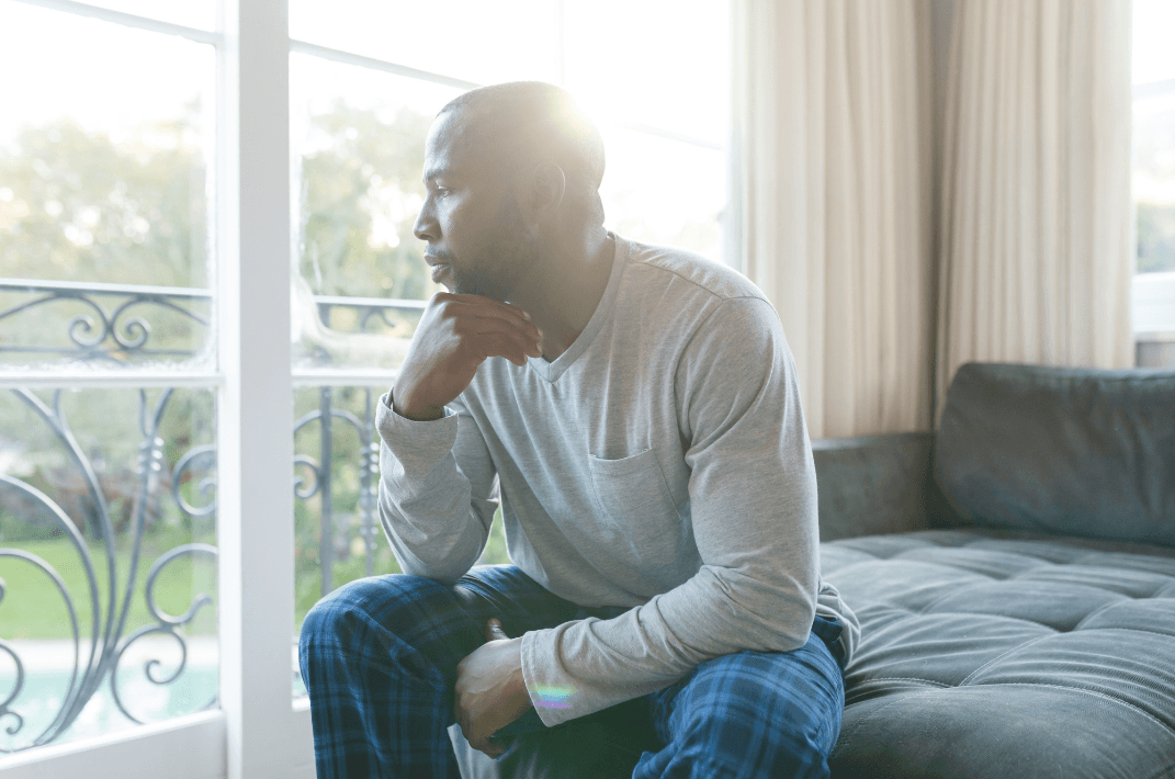 Man sitting thoughtfully by a window, representing psychological factors that can contribute to premature ejaculation.