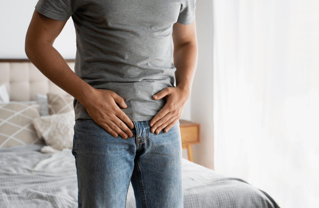 Man holding his lower pelvic area while experiencing symptoms associated with Peyronie's disease.